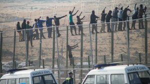 Would-be immigrants stand atop a boarder fence separating Morocco from the north African Spanish (AFP, 2014)