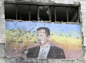 A picture of Bashar al-Assad riddled with holes on the facade of the police academy in Aleppo, after it was captured by Free Syrian Army fighters, March 4, 2013. (REUTERS/Mahmoud Hassano)